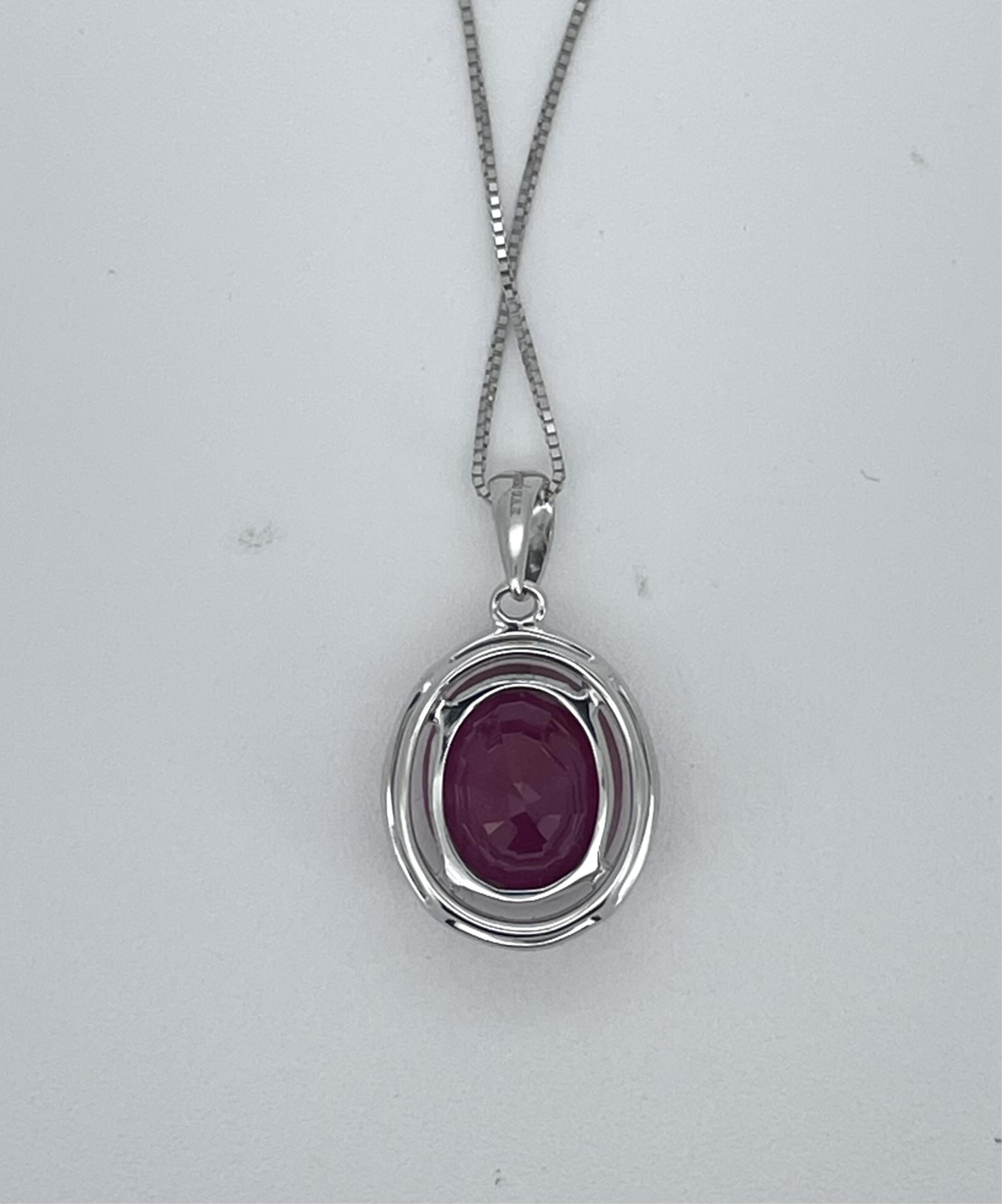 A modern 750 white metal, ruby and diamond cluster set oval pendant, overall 12mm, on a 750 white metal chain, 42cm, gross weight 3.1 grams.